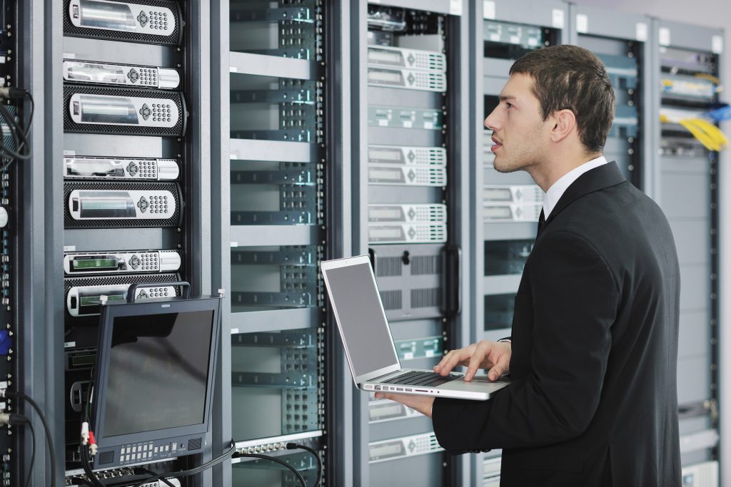 professional using laptop in server room working on network design